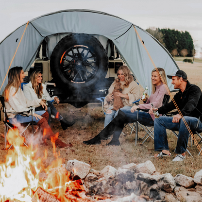 Friends enjoying campfire under Trail Gear Oasis Jeep Trail Cover and Sun Shade canopy