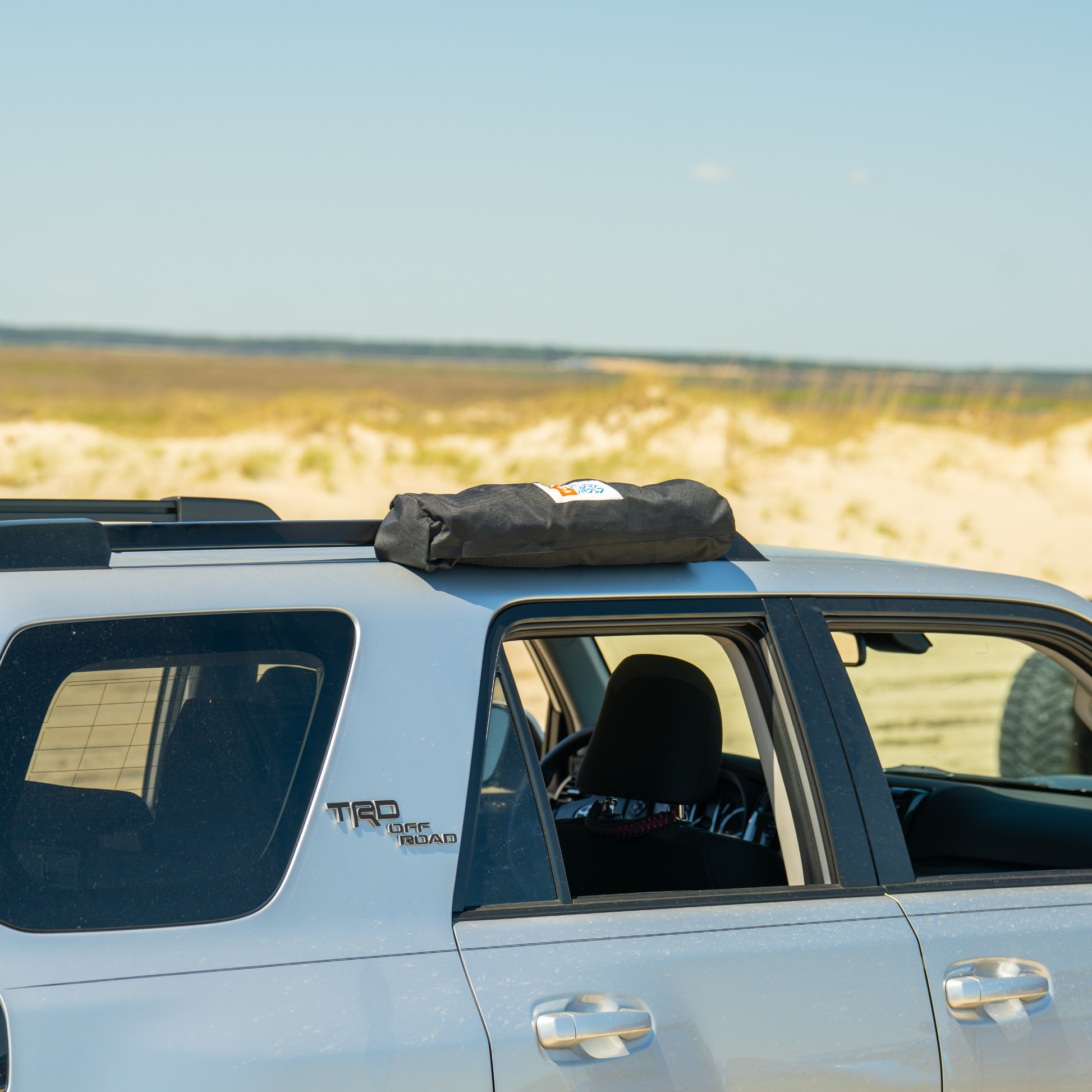 Trail Gear Oasis SUV sun shade bag mounted on vehicle roof rack with branded logo label visible