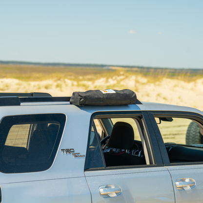 Trail Gear Oasis SUV sun shade bag mounted on vehicle roof rack with branded logo label visible