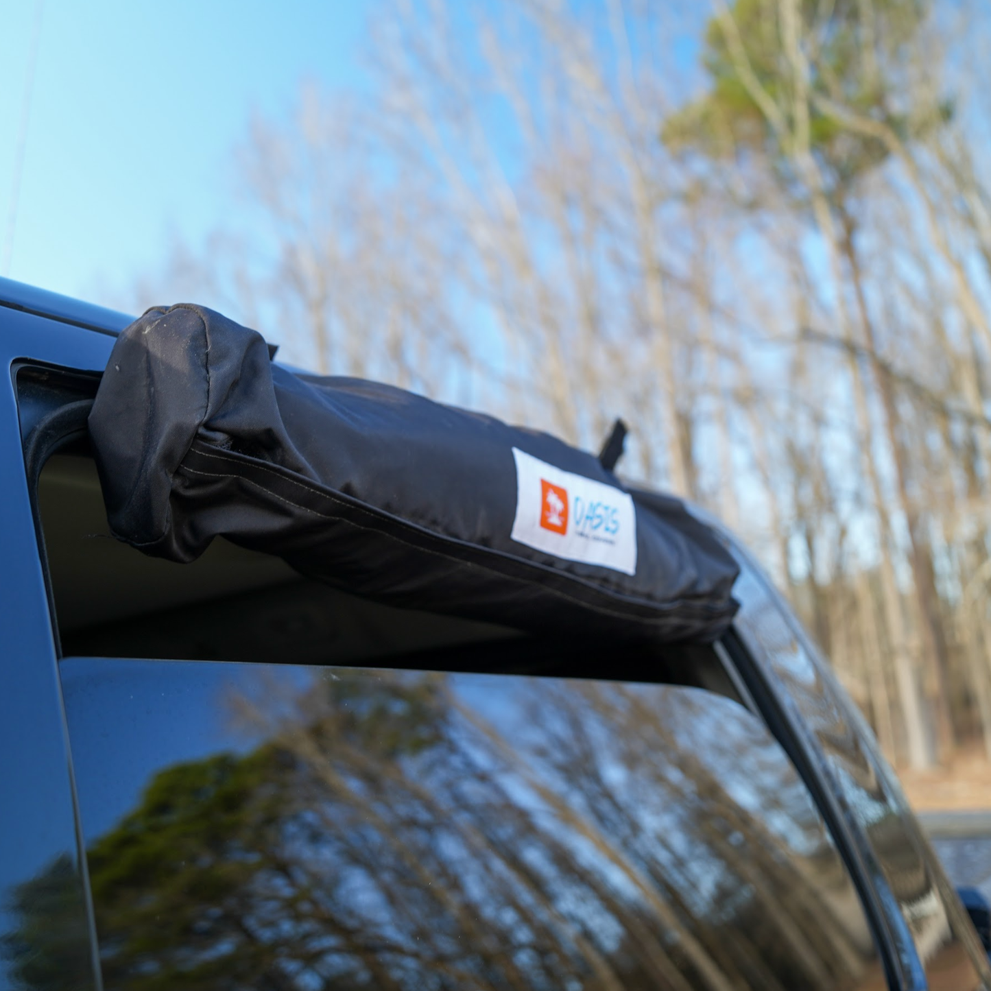 Trail Gear Oasis sun shade roll bag with branded label mounted on truck door