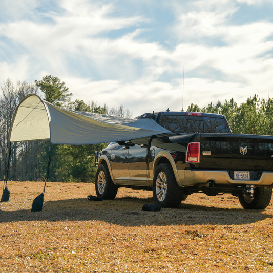 Trail Gear Oasis truck trail cover fully deployed on Ram pickup in open field showing complete shade setup