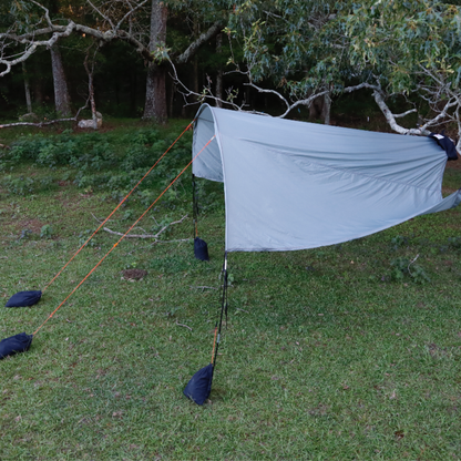 Side view of Trail Gear Oasis Sidekick Shade tree-mounted setup with support pole and sandbag weights at dusk