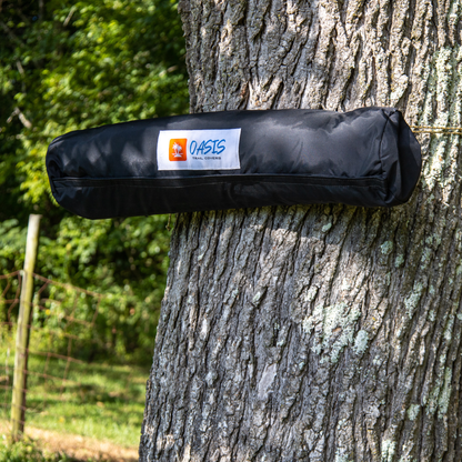 Trail Gear Oasis branded storage bag strapped to tree trunk showing portable mounting system for Sidekick Shade
